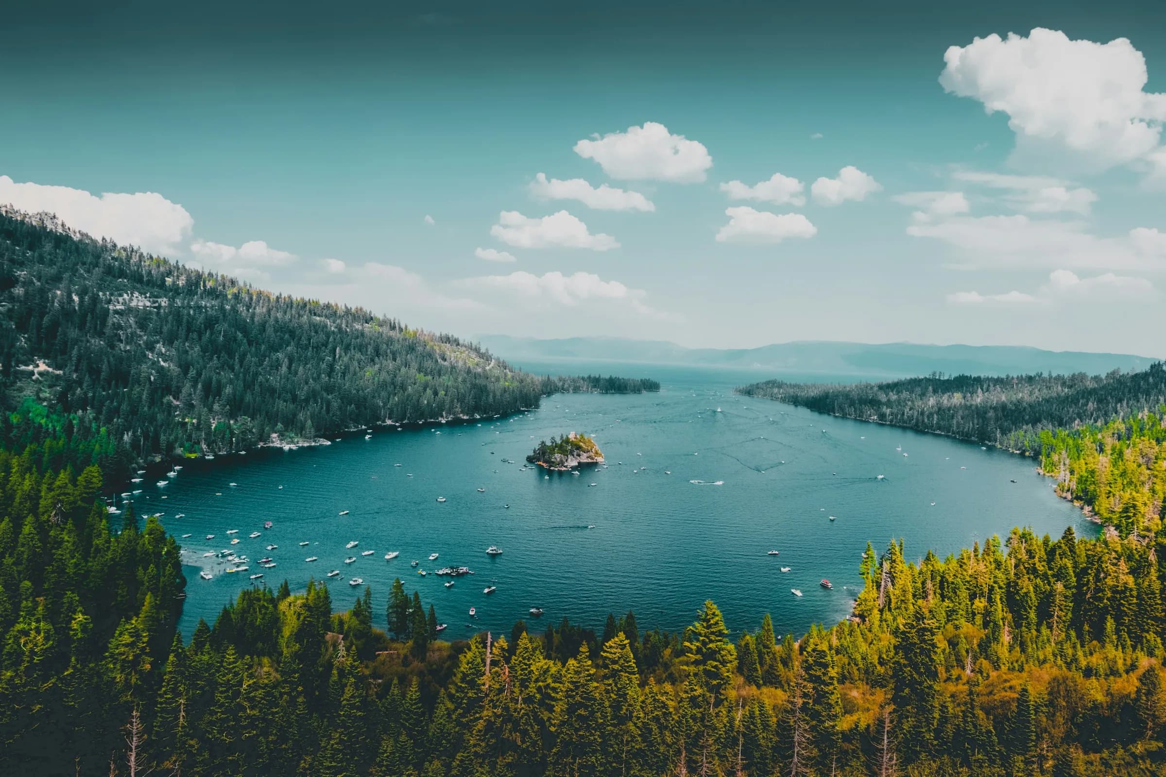 Emerald Bay on Lake Tahoe from above, boats scattered around Fannette Island and pine forest down to the water