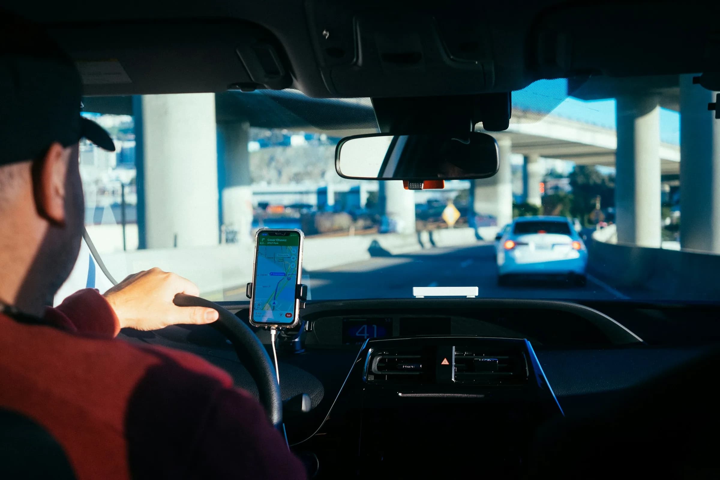 Driver behind the wheel with a navigation app on a phone mounted to the dashboard
