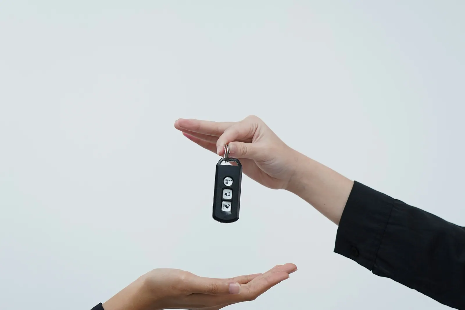 One hand passing a car key fob into another’s open palm
